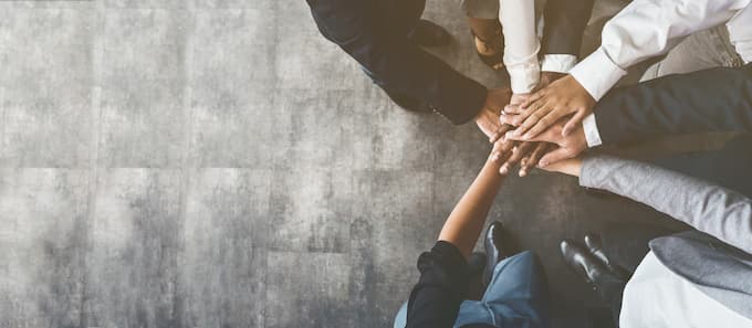 Karriere-Jobs-bei-EWE 7 unterschiedliche Menschenhände stehen im Kreis und legen ihre Hände zusammen.